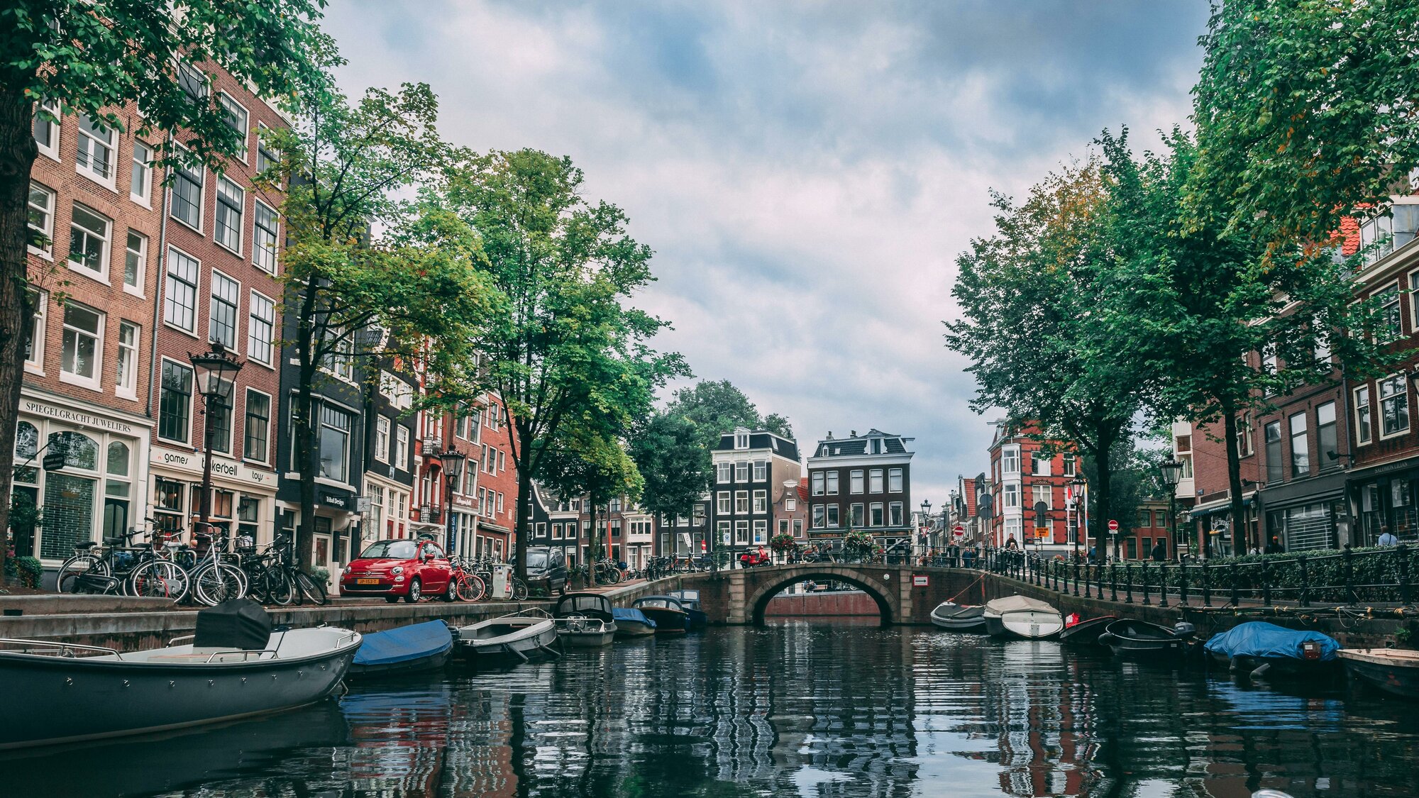 Shot from a boat floating along a canal, a quaint view of Amsterdam bridges, boats, and buildings