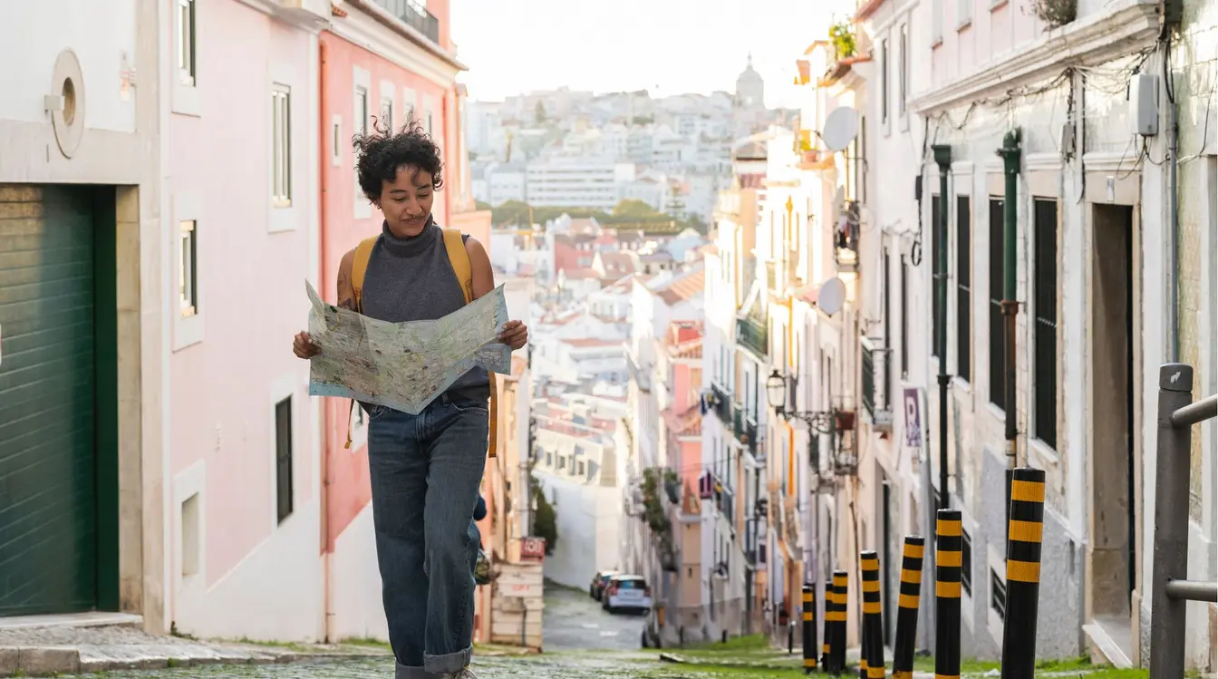 Jovem turista desbravando as ruas do bairro histórico de Alfama, buscando atividades para fazer em Lisboa.