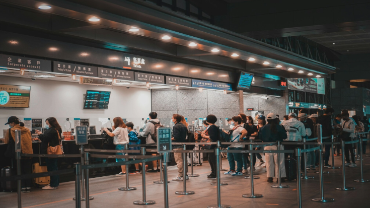 People queuing in a train station to get tickets.