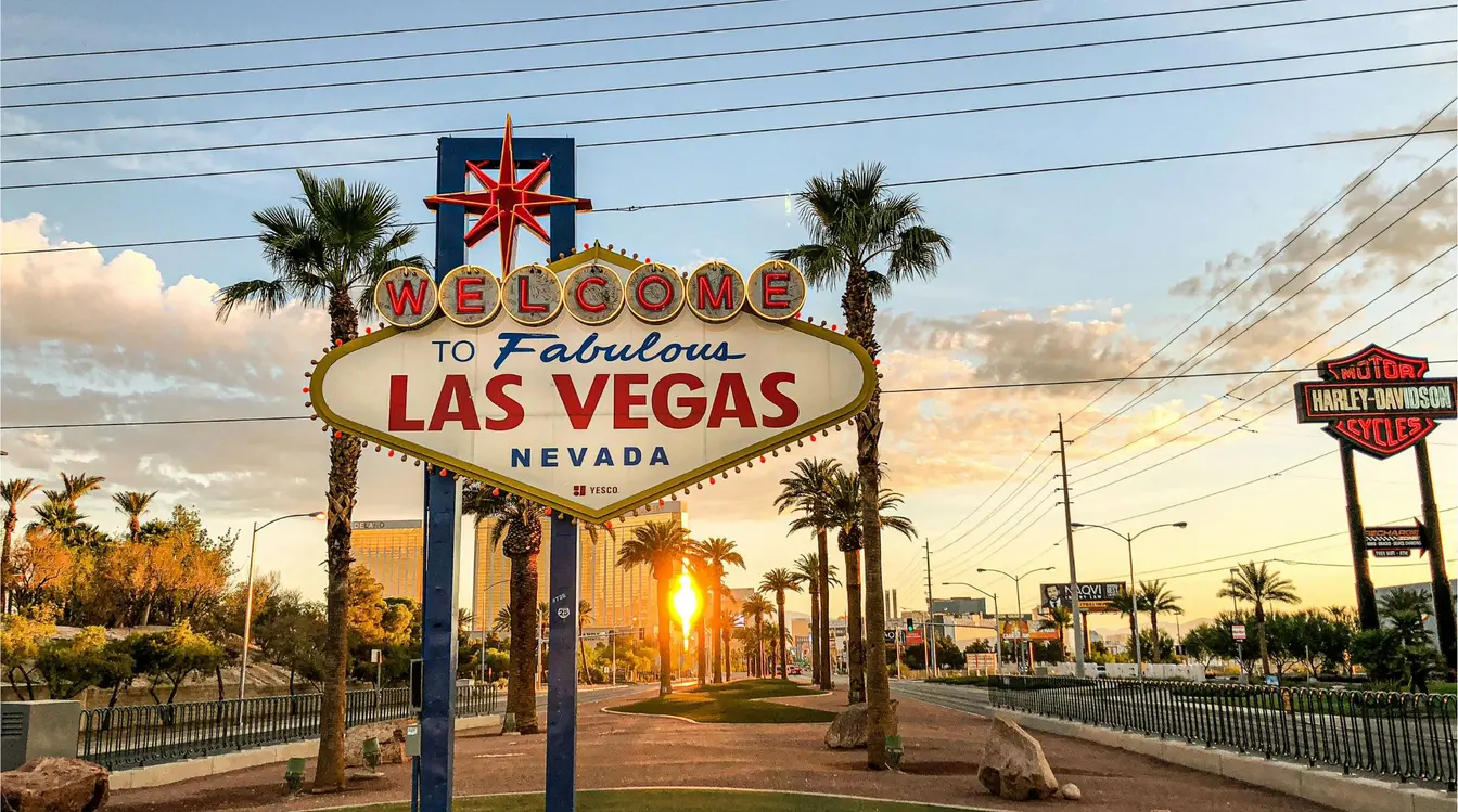 Letrero “Welcome to Fabulous Las Vegas” al atardecer, con palmeras y cielo parcialmente nublado.