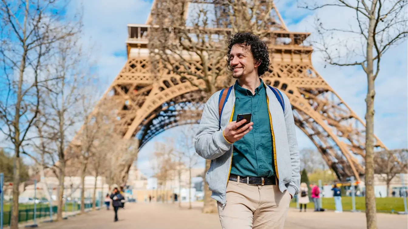 Ein Mann läuft während der Fashion Week 2027 durch Paris und schaut aufs Handy