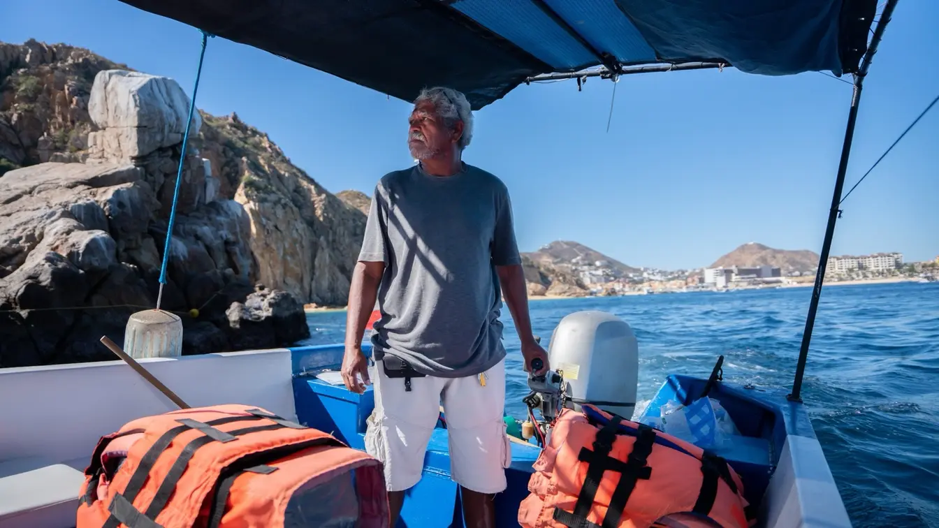 Capitán de barco navegando frente a las formaciones rocosas de Cabo San Lucas