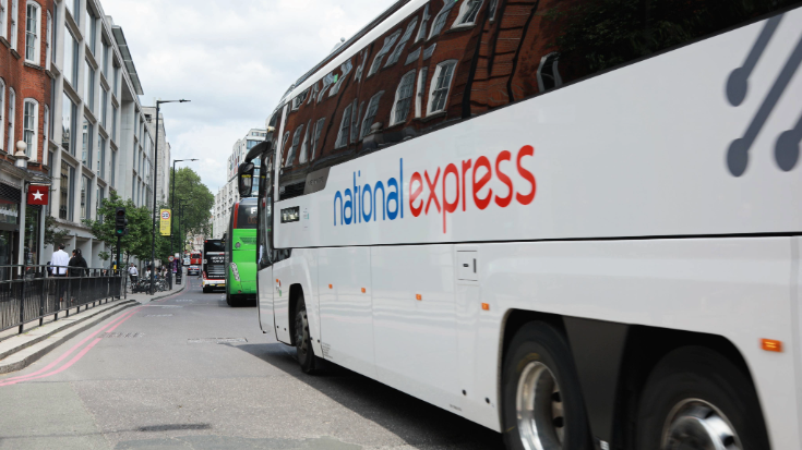 The side of a National Express bus showing the brand's famous blue and red logo, outside of London's Victoria coach station.