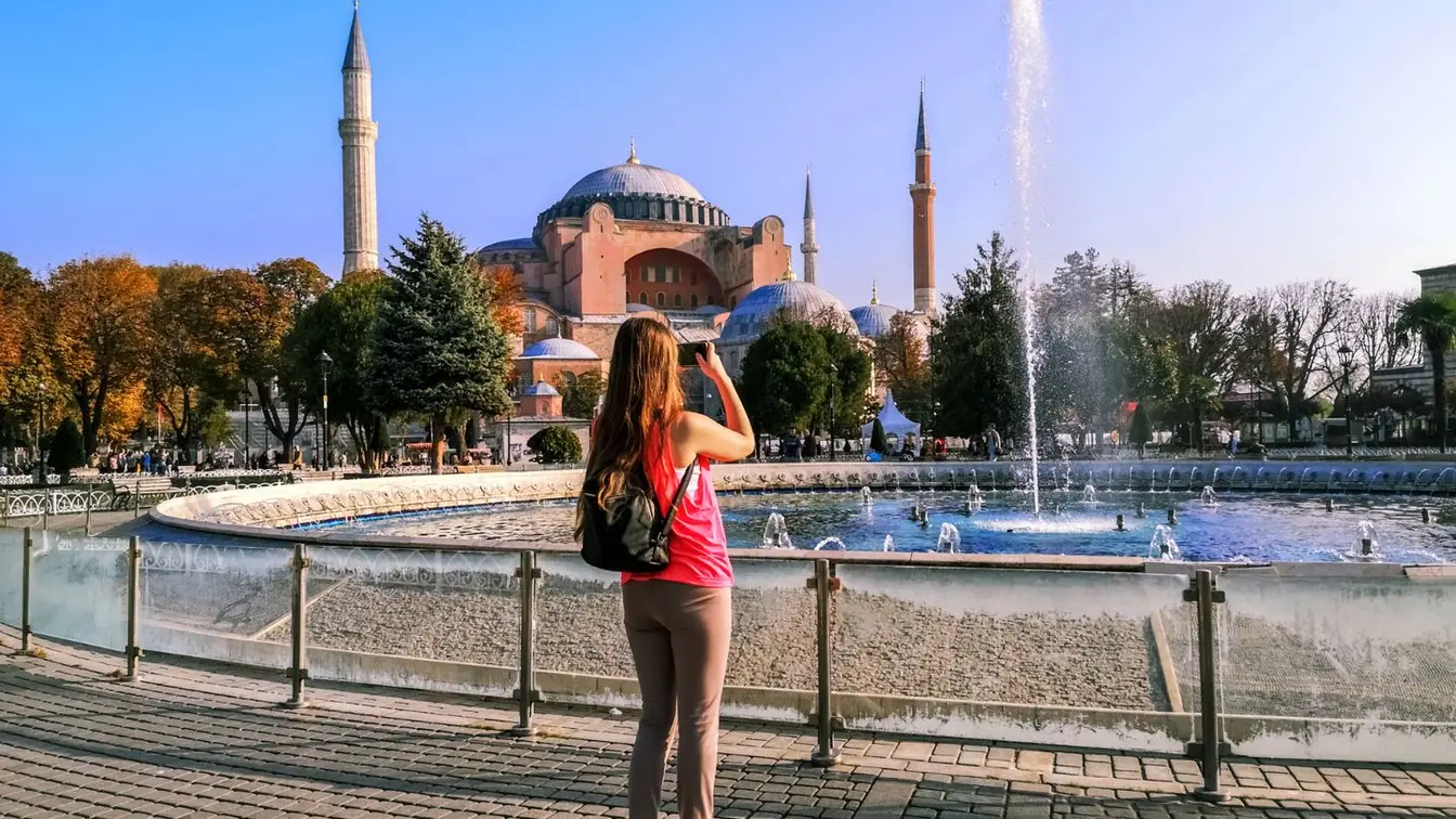 Eine Frau steht in Istanbul vor einem Brunnen und benutzt mobile Daten in der Türkei.