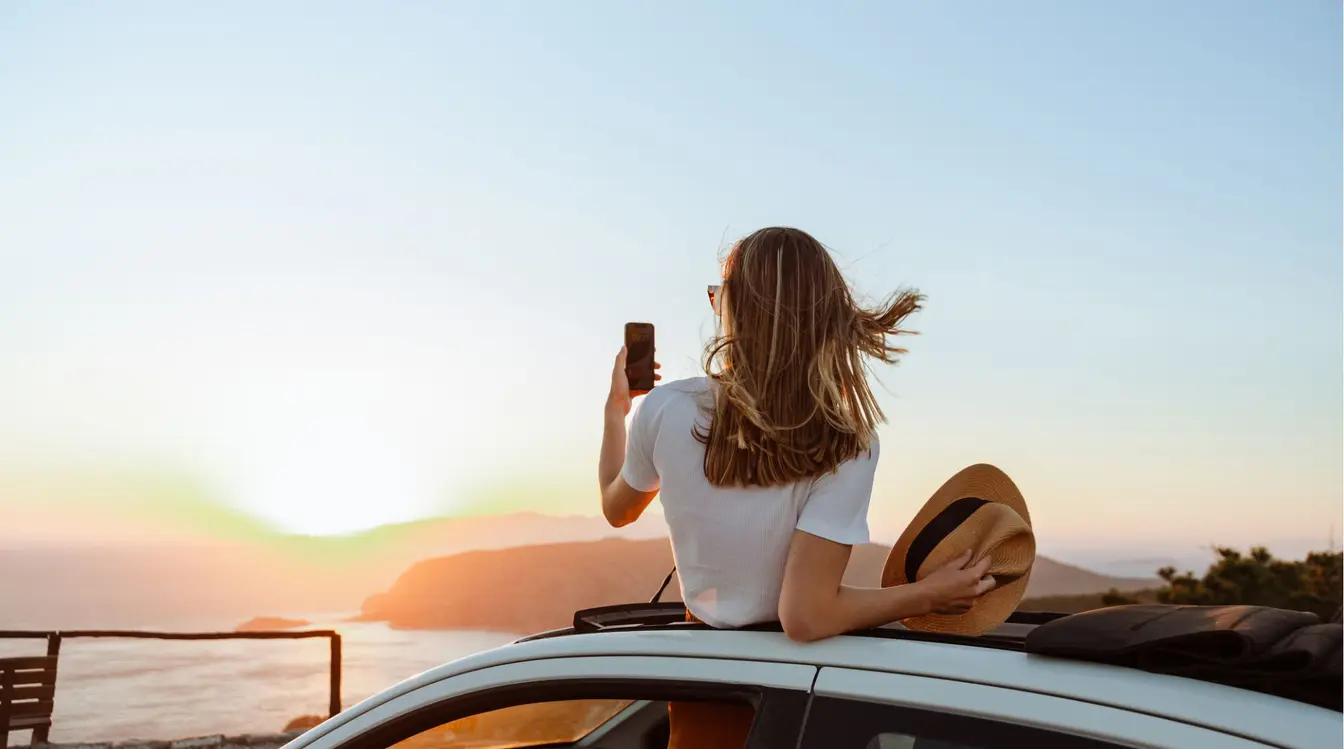 Jeune femme photographiant un coucher de soleil depuis un belvédère en Europe.