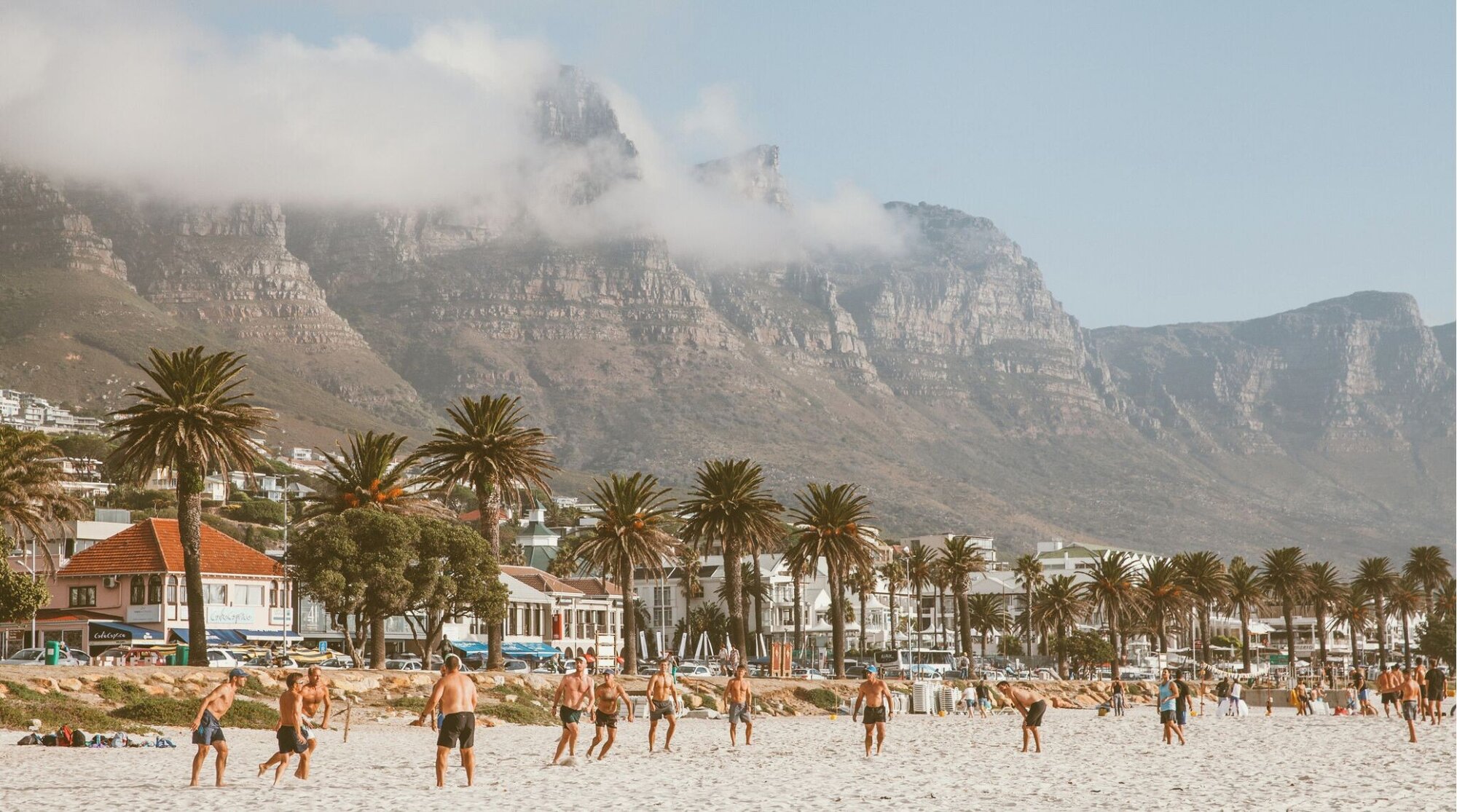 Turistas aproveitando a praia de areia branca e tomando sol em Camps Bay, Cidade do Cabo, África do Sul