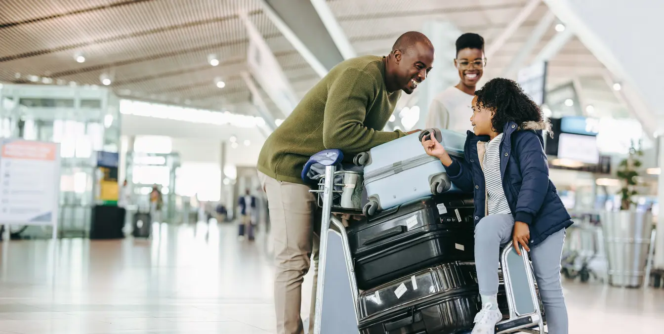 Una familia que lleva un carro lleno de valijas en el aeropuerto para ilustrar el ESTA para viajar a Estados Unidos.