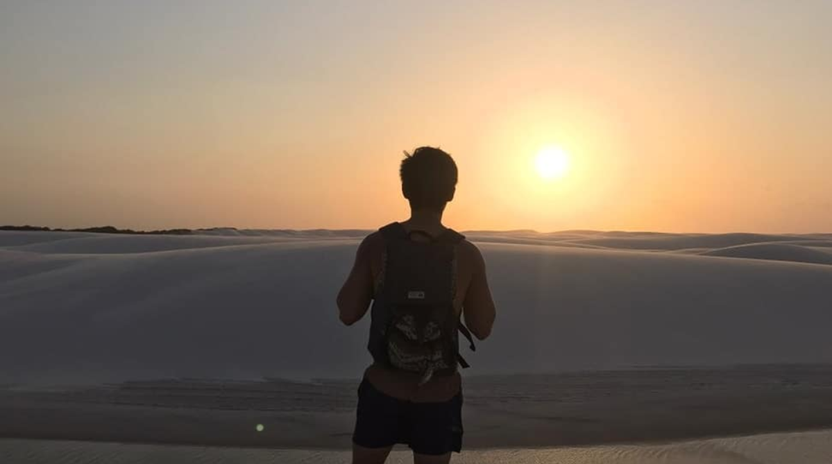 A man staring into the sunset at Lençóis Maranhenses National Park