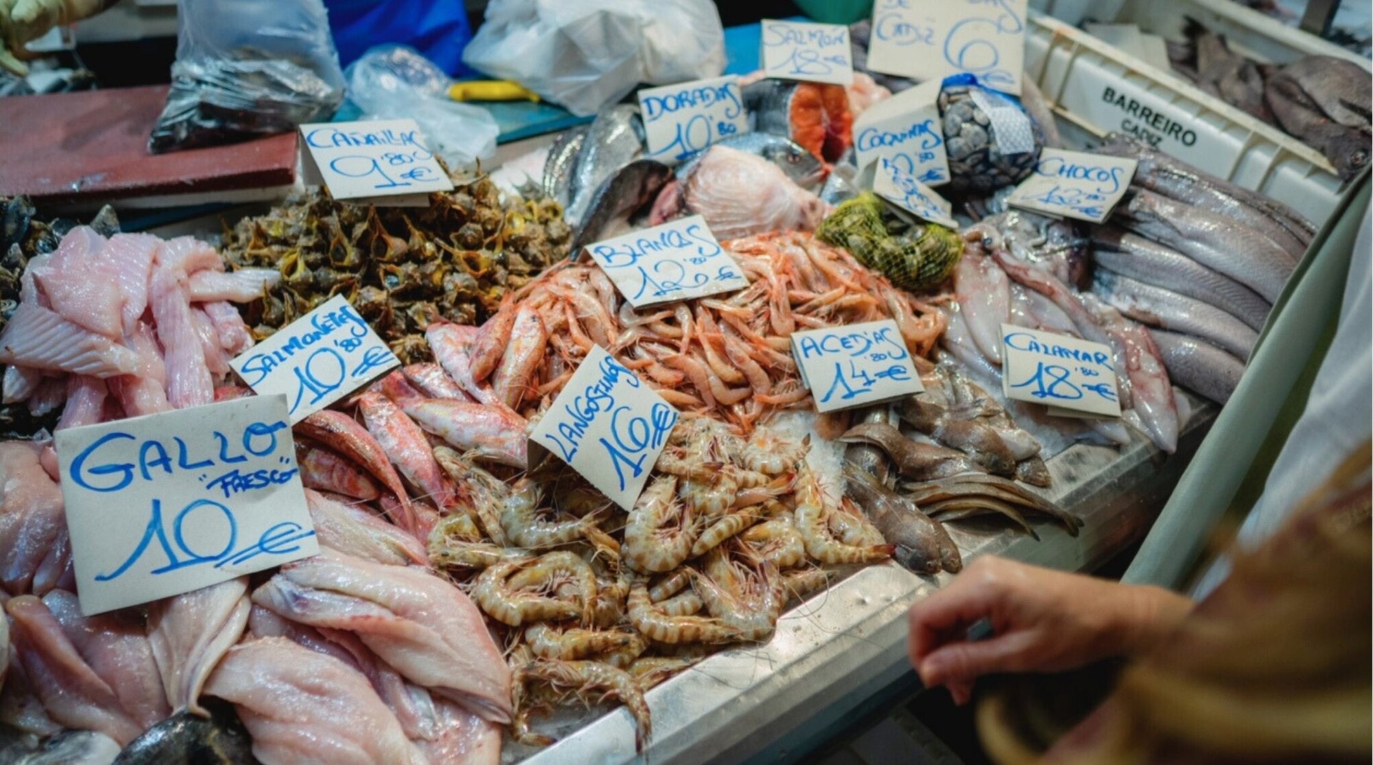 Puesto de mariscos frescos con precios en un mercado de Barcelona.