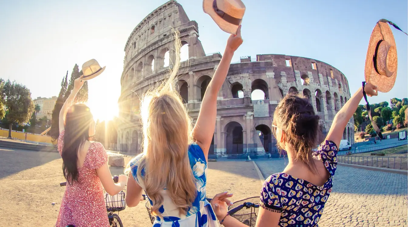 Trois jeunes femmes voyageuses souriantes portant des chapeaux pendant leurs vacances.