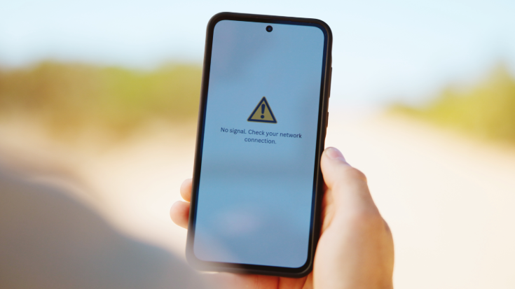 A close up of a hand holding a phone, with a message on the screen stating 'No signal. Check your network connection', to illustrate a blog post entitled 'How to Know if Someone Blocked You on WhatsApp.'