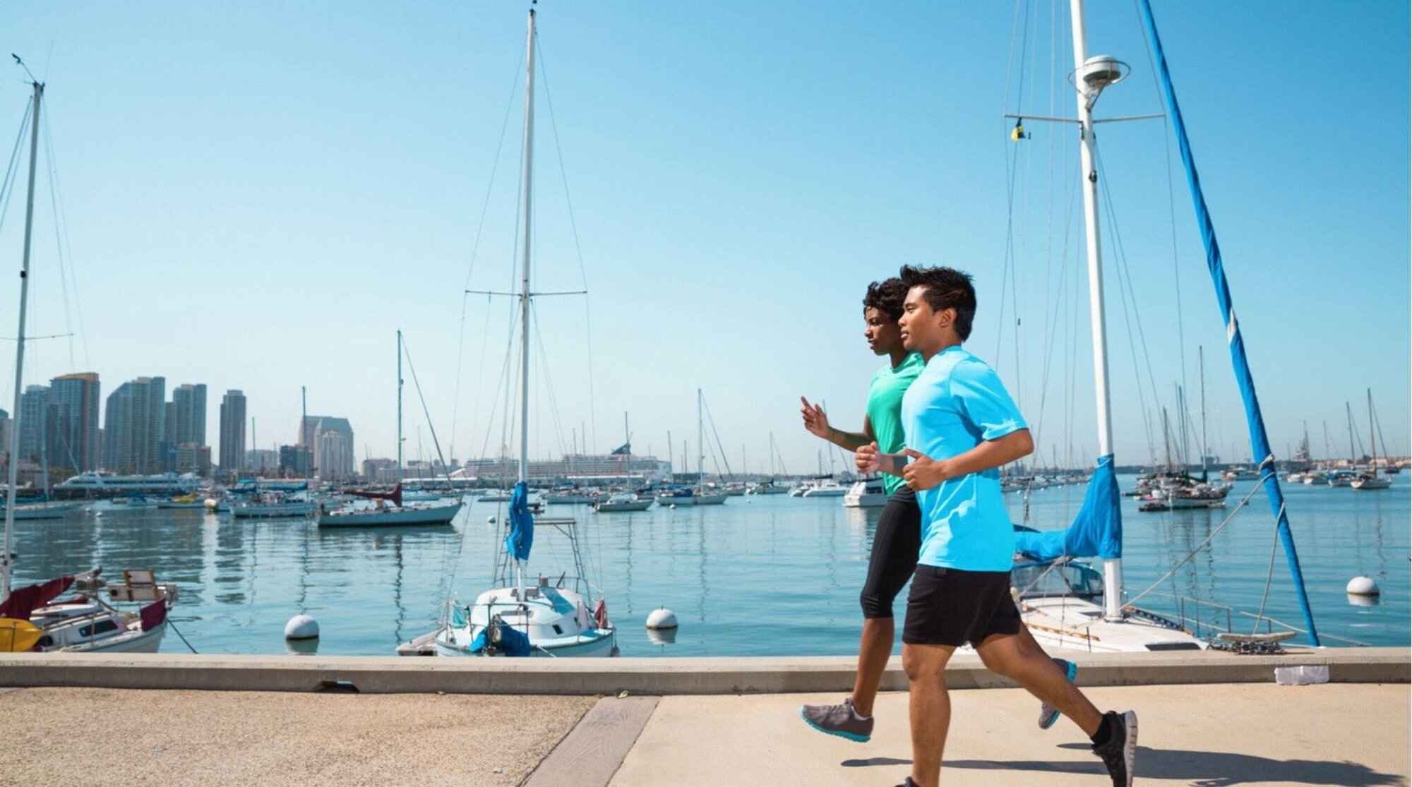 Corredor haciendo ejercicio junto a la bahía y los barcos en San Diego.