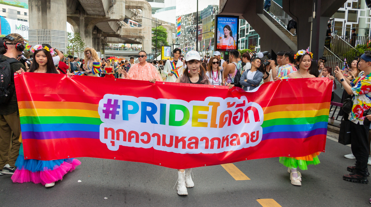 Bangkok Pride parade marchers holding a rainbow banner