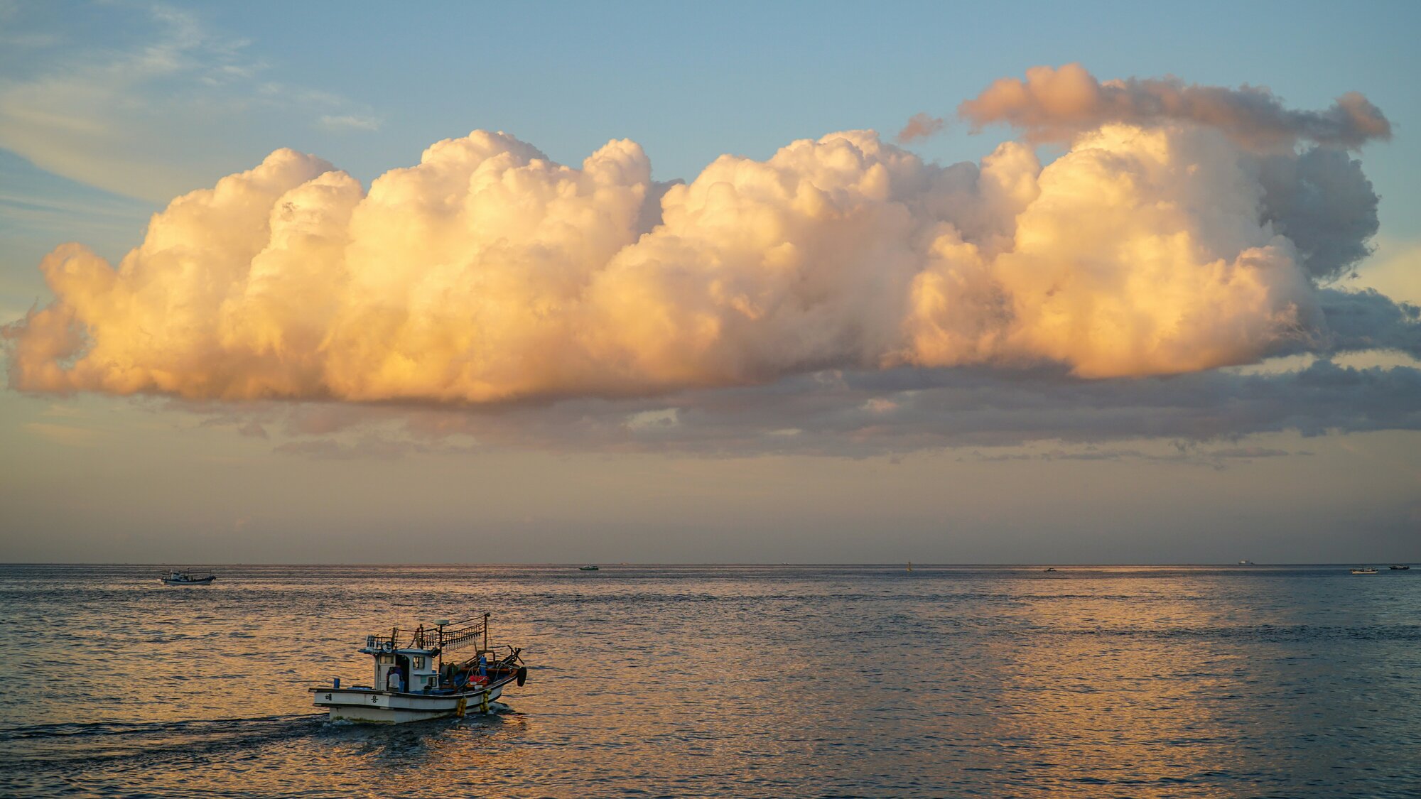 Calm waters and a single fishing boat at golden hour near Jeju Island