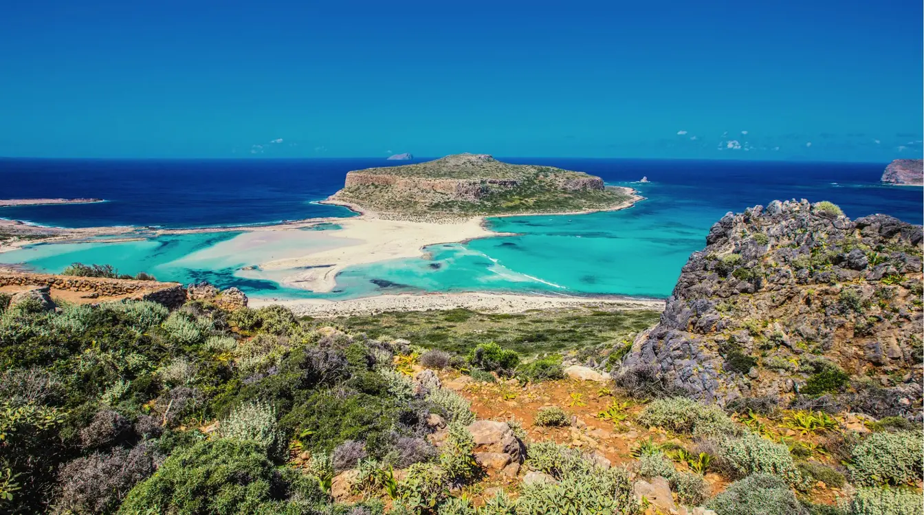 Vue panoramique de la plage de Balos en Crète, avec son lagon turquoise, son sable blanc et ses eaux cristallines.