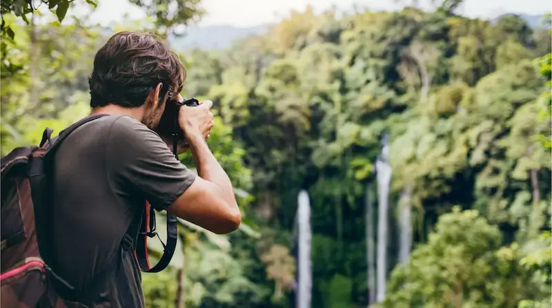 Viajero tomando fotografías de una cascada en medio de la selva en una excursión