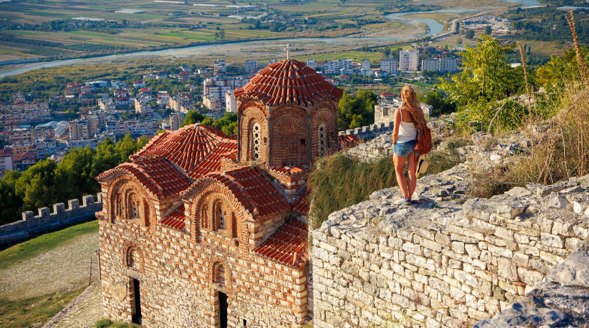Frau, die die Heilig-Dreifaltigkeits-Kirche und das Stadtpanorama in der Burg Berat, Albanien betrachtet