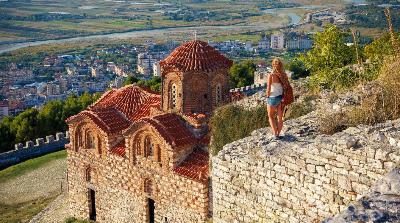 Frau, die die Heilig-Dreifaltigkeits-Kirche und das Stadtpanorama in der Burg Berat, Albanien betrachtet