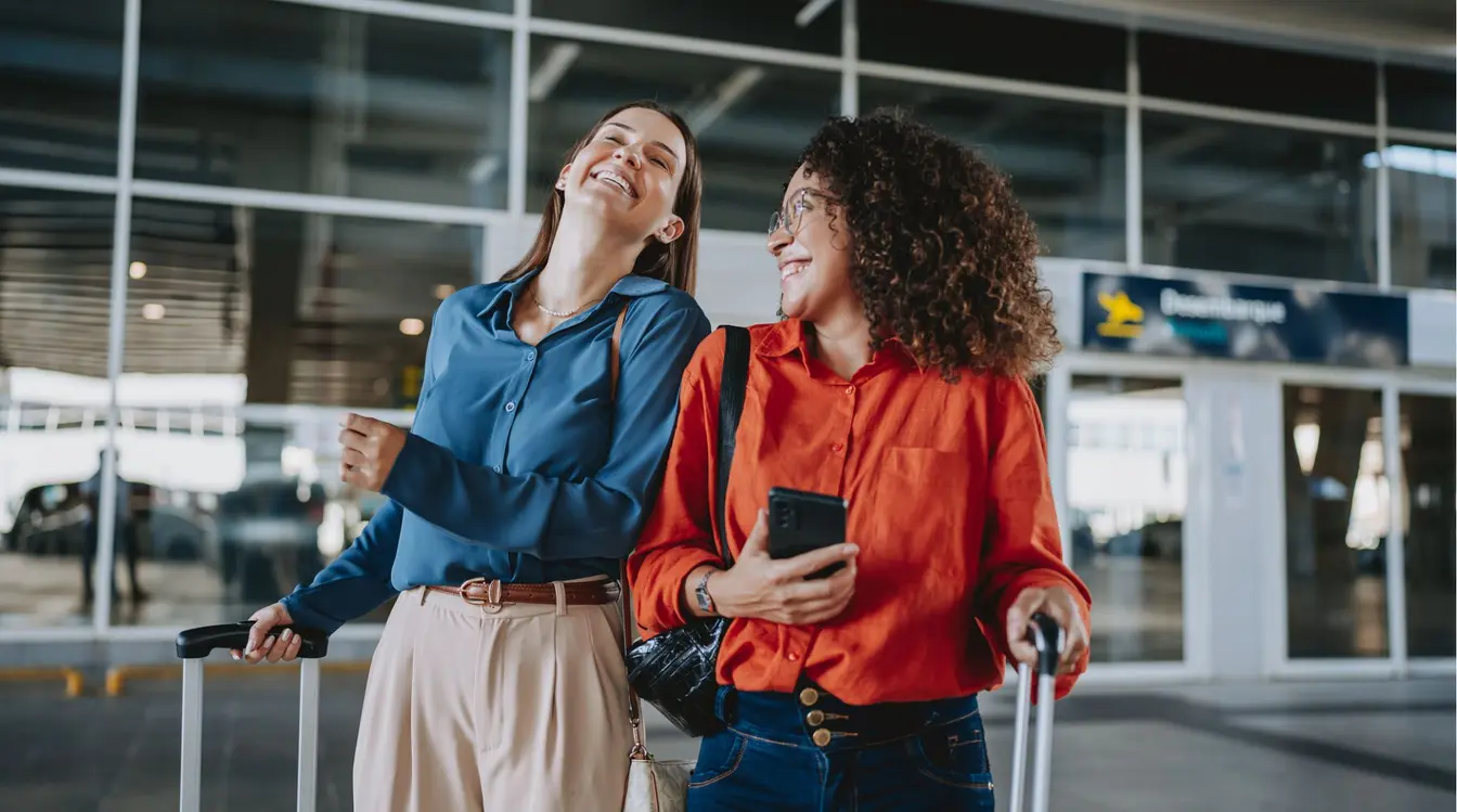 Amigas viajantes no aeroporto felizes pois vão conhecer novos destinos.