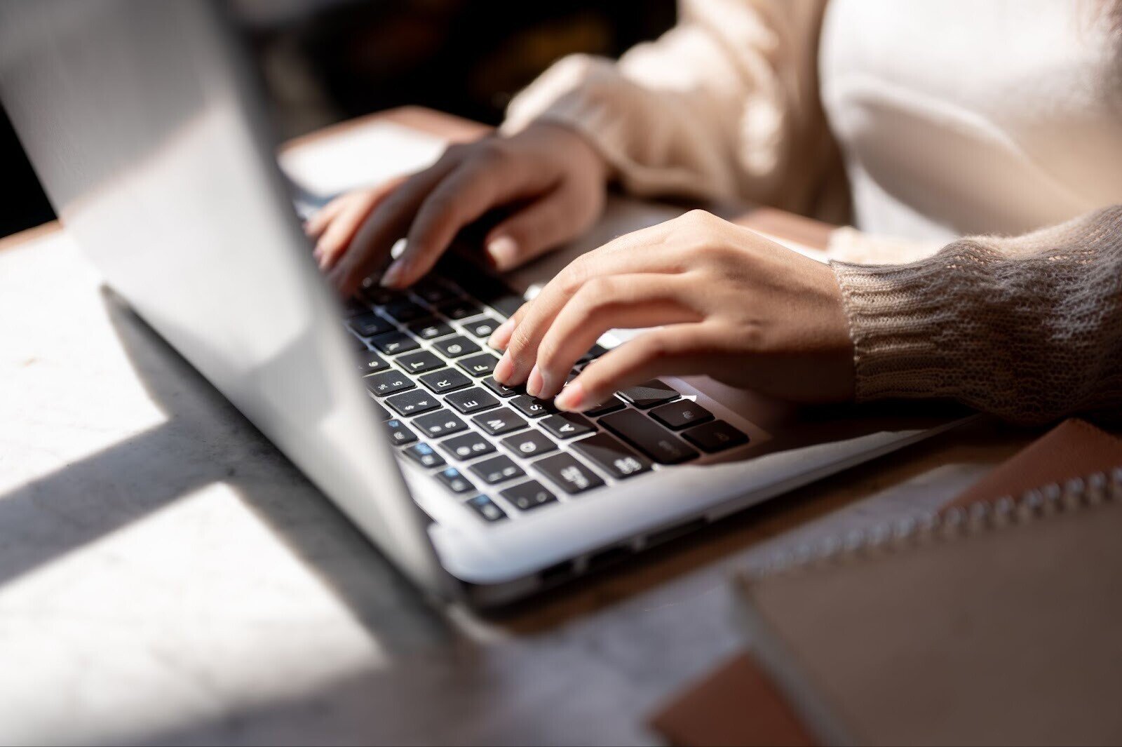 Woman's hands typing away on a laptop computer, booking sleeper trains in Europe online