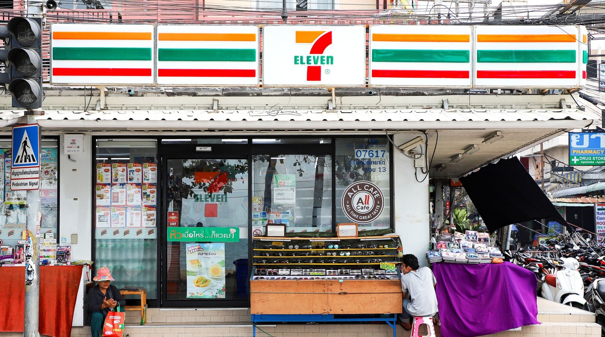 Front view of a 7-Eleven convenience store on a city street in Thailand.