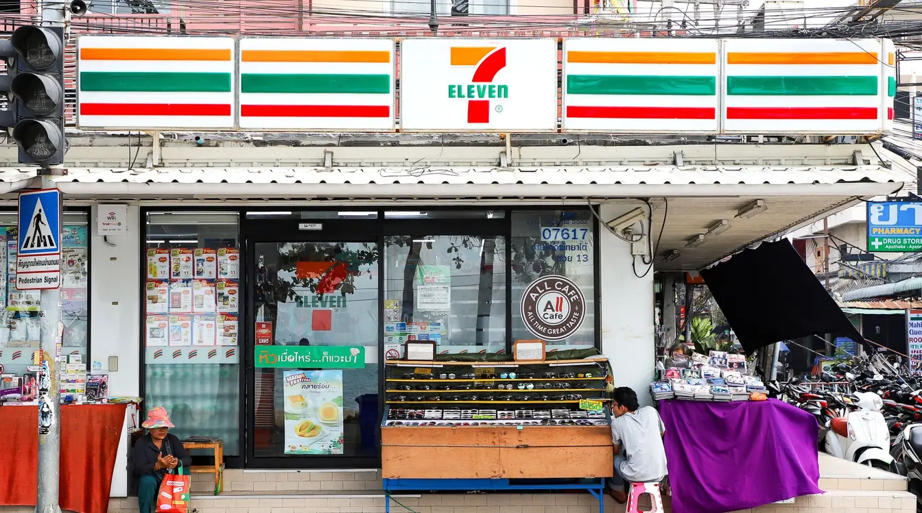 Front view of a 7-Eleven convenience store on a city street in Thailand.
