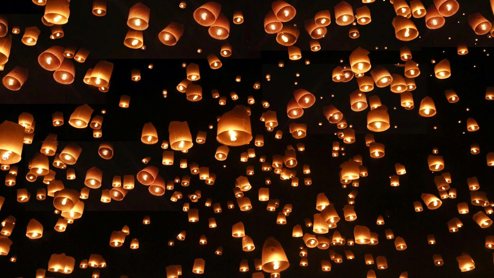 Lanterns flying up towards the sky at night