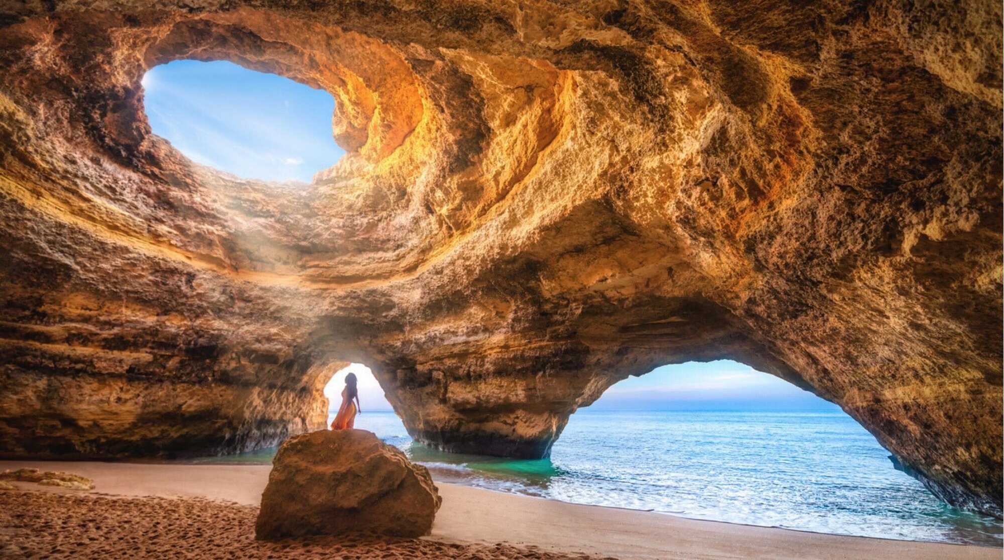 Mulher sozinha sob a luz do sol na gruta natural do Mar de Benagil, no Algarve, Portugal.