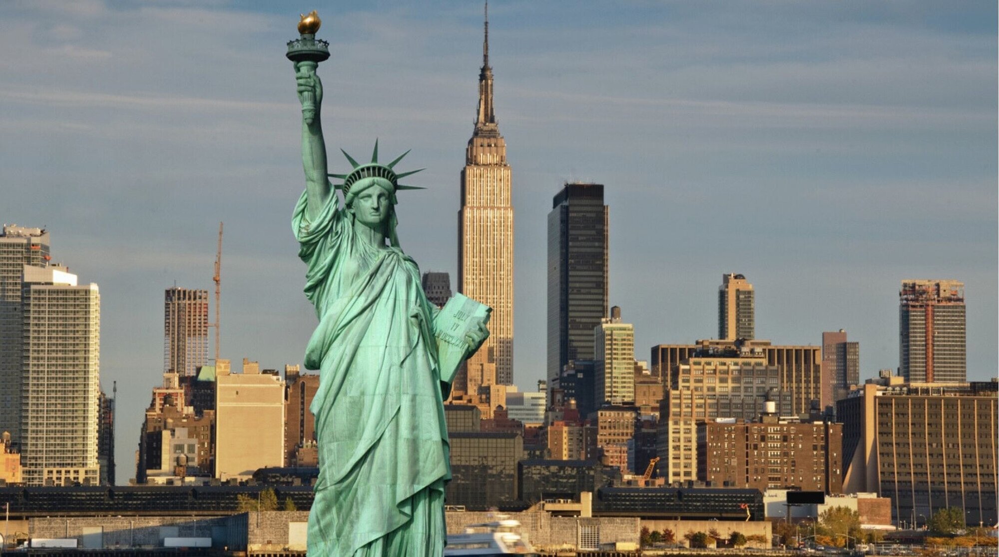 La Estatua de la Libertad y el Empire State en una misma escena, dos símbolos históricos de Nueva York.