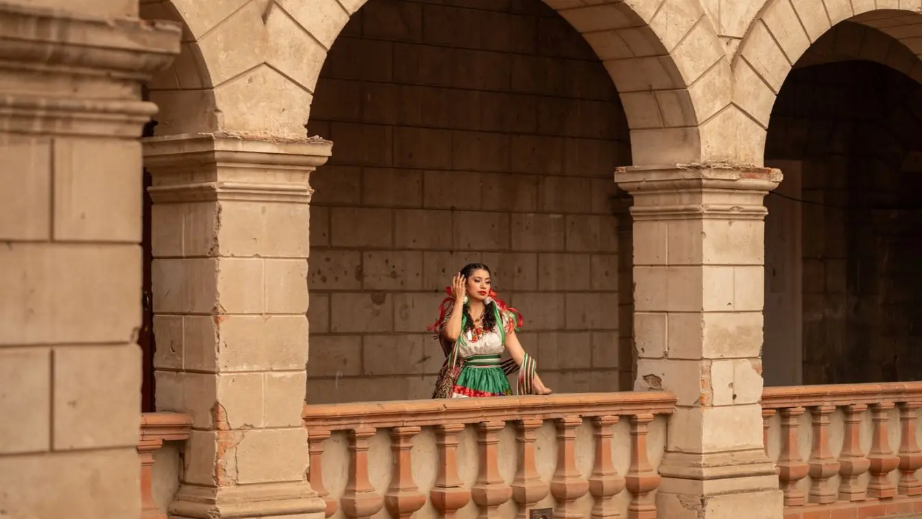 Mujer caminando por Guadalajara entre arcos de cantera, en un recorrido entre distintas zonas de la ciudad.