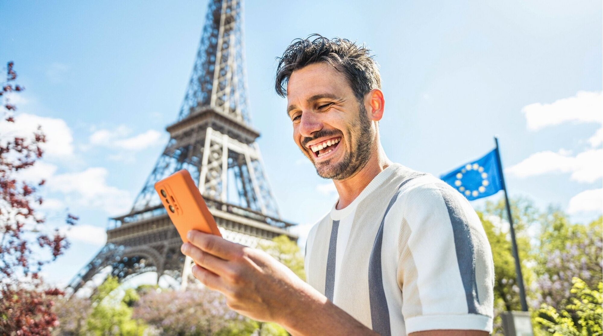 Turista mirando el móvil en París tras confirmar que su teléfono es compatible con eSIM.
