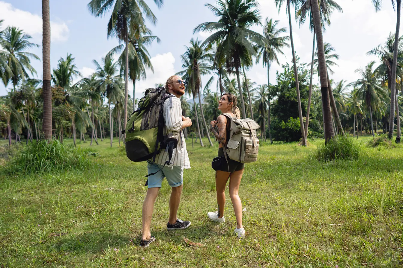 Backpackere på en sti mellom palmer i Thailand