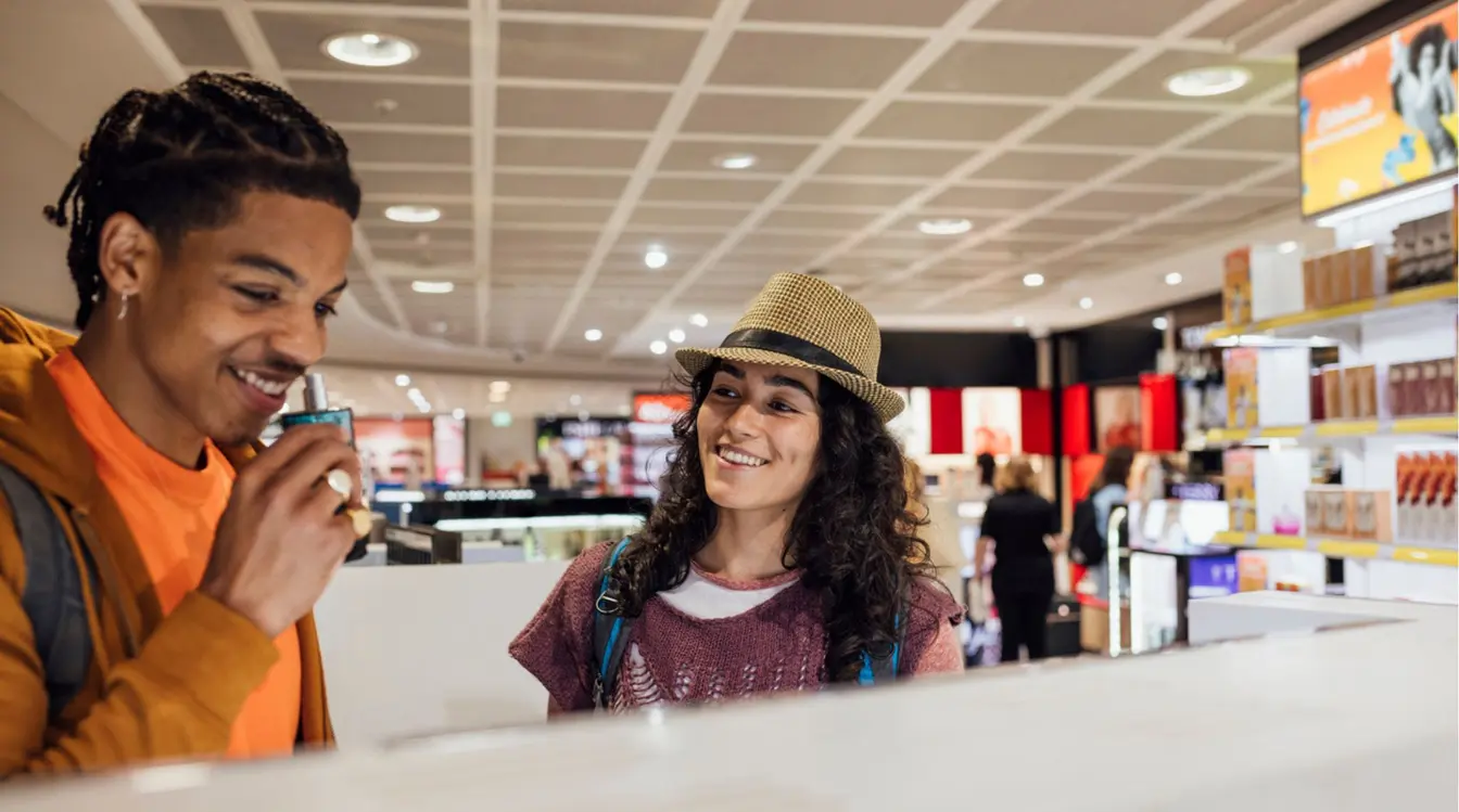 Casal de turistas experimentando perfumes em loja de cosméticos no Duty Free dos aeroportos.