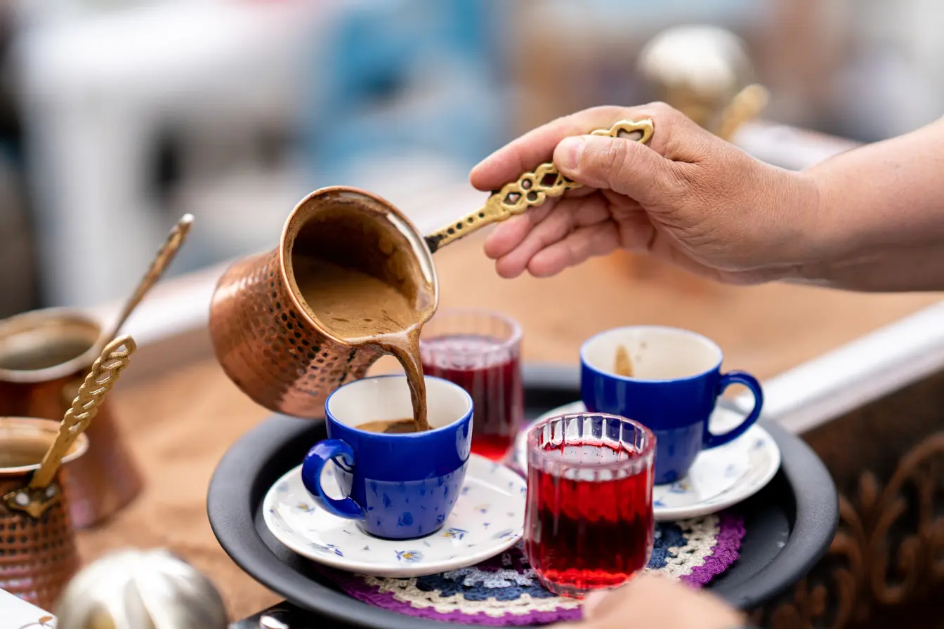 Preparazione del caffè turco su sabbia calda con cezve, metodo tradizionale riconosciuto dall’UNESCO