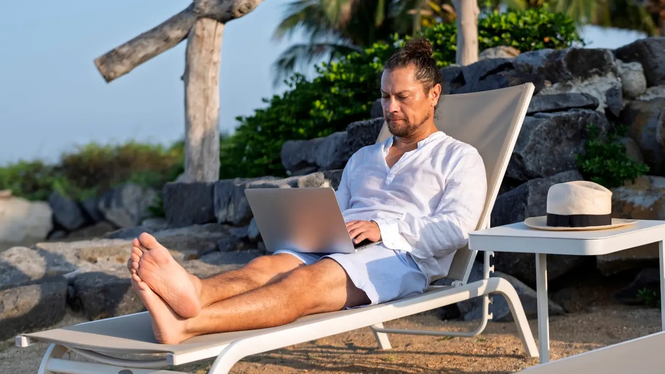 Hombre trabajando en una laptop desde una terraza frente al mar en Los Cabos