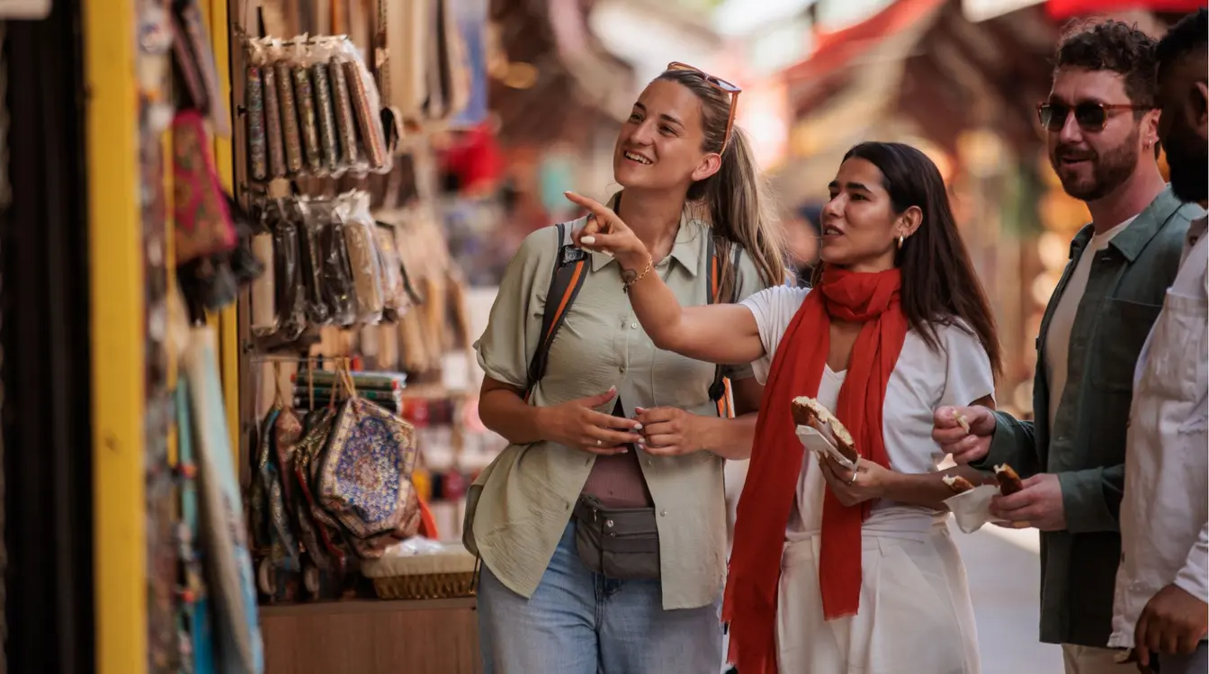 Grupo de turistas explorando as barracas de artesanato e têxteis do Grande Bazar de Istambul, na Turquia.