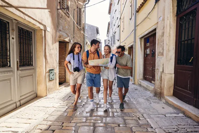 Grupo de turistas caminando por una calle empedrada mientras consulta un mapa de papel.