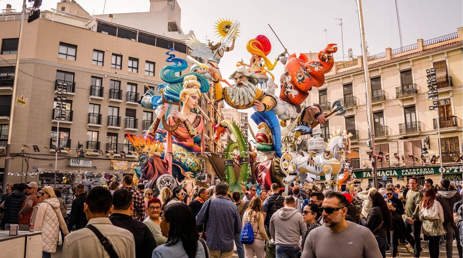Turistas caminhando pela rua em frente a uma escultura de Fallas, no centro de Valência, em março, apreciando a chegada da primavera.