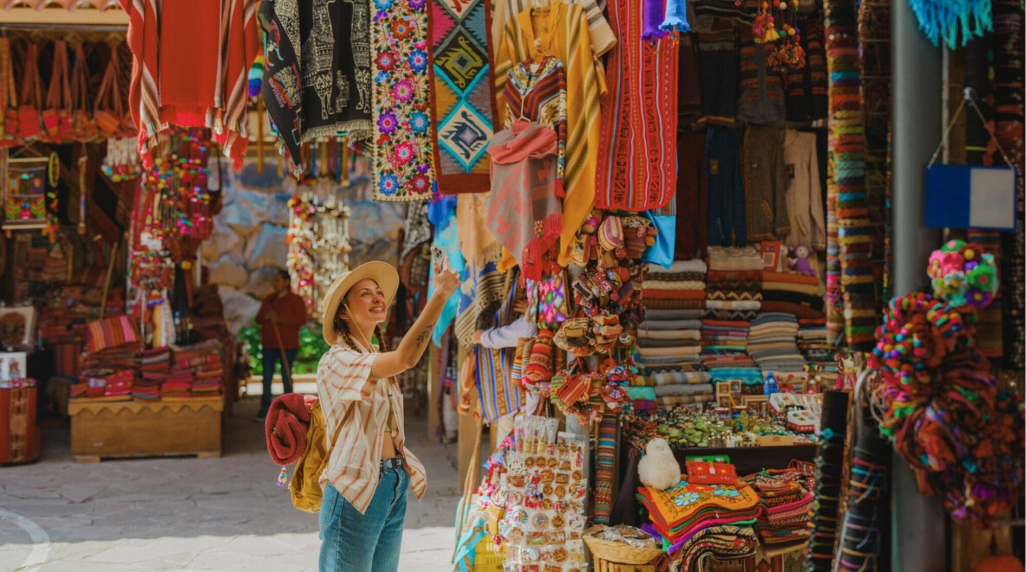 Viajera sacando fotos con el móvil en un mercado; cuánto cuesta una eSIM y de qué depende.
