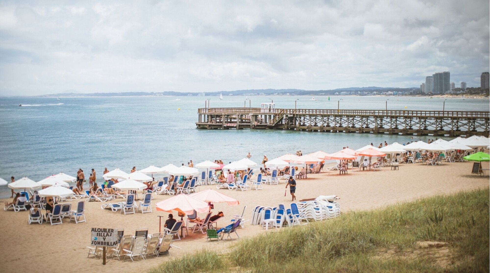 Turistas relaxando durante uma manhã ensolarada de verão na Praia Mansa, em Punta del Este. Vista ampla a partir das dunas da praia.