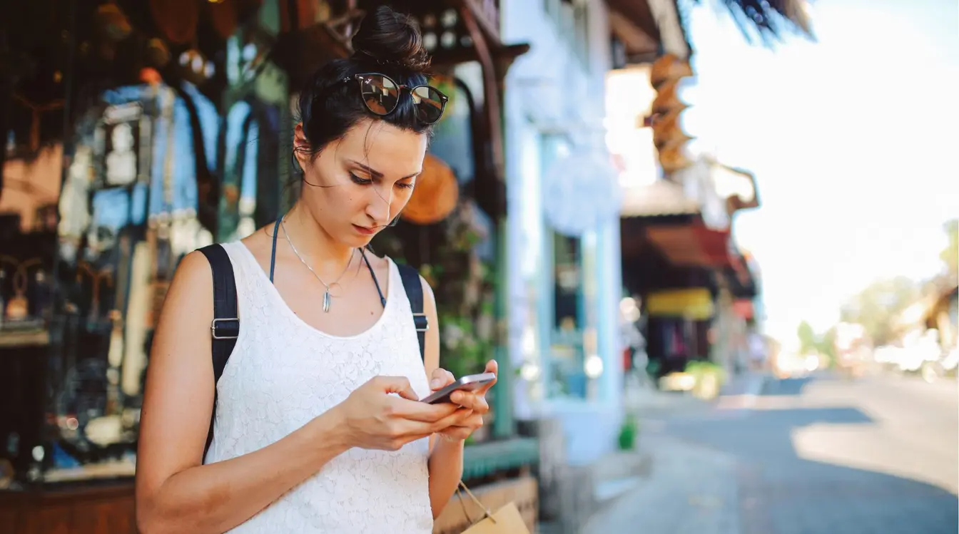  A woman stood on a street in Bali using an eSIM on her phone.