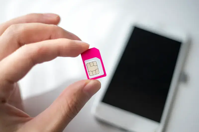 Una mano mostra una SIM card con la migliore offerta roaming estero
