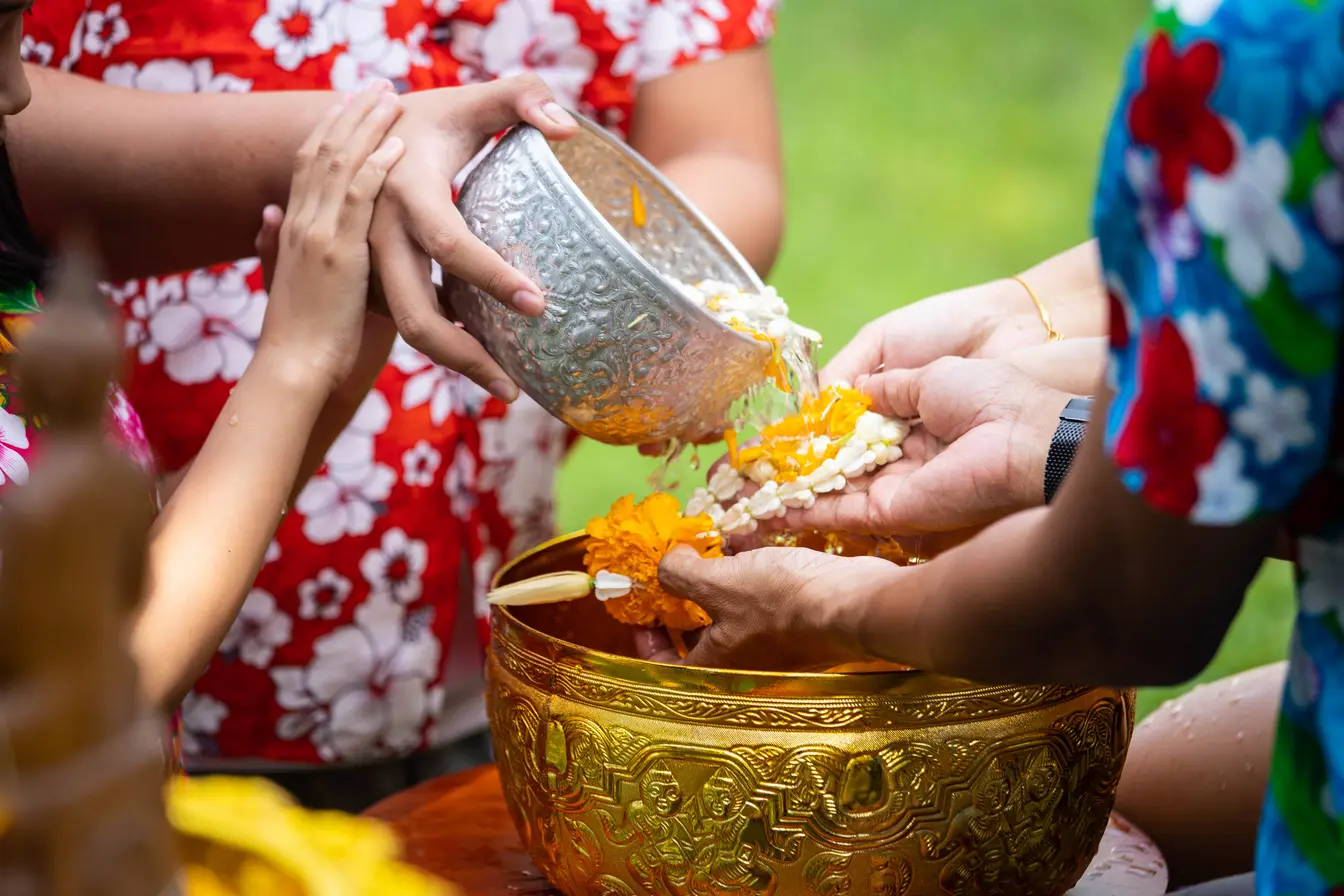 Young girl pouring water on the elders' hands during Songkran.