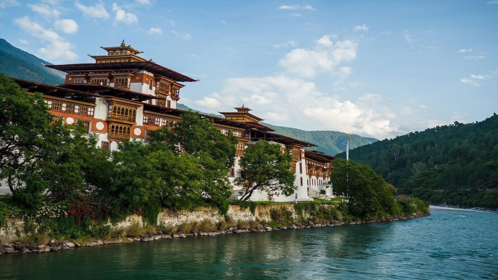 A brown and white building surrounded by trees, with a mountain in the background in Punacha, Bhutan