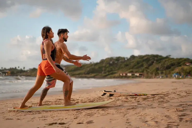 nstructor enseñando a surfear en la playa de Puerto Escondido en marzo, con clima soleado