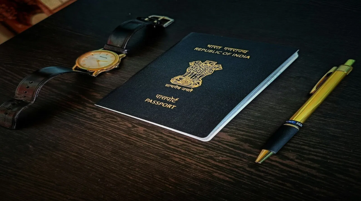 An mage of an Indian passport on a dark brown wooden desk.