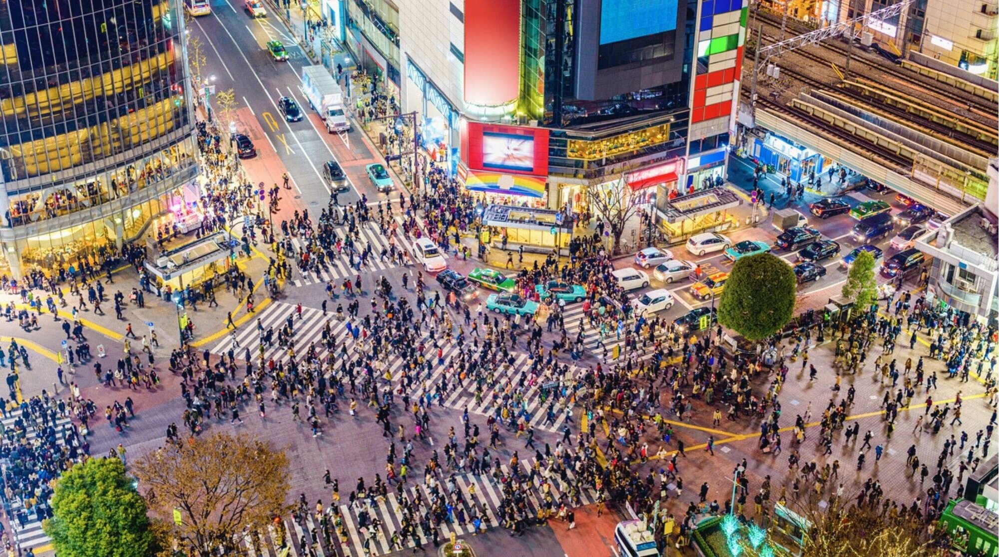Cruce de Shibuya en Tokio con multitud de personas y edificios iluminados.