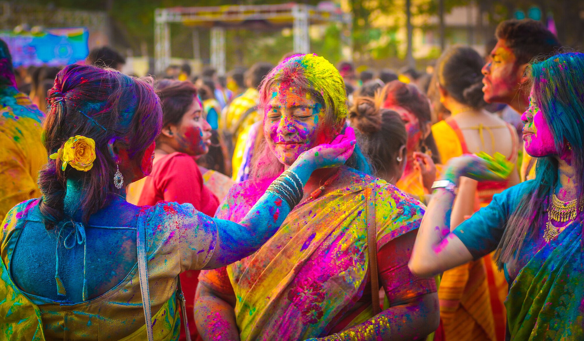 Eine Frau trägt einer anderen Frau beim Holi Fest in Indien Farbe aufs Gesicht auf