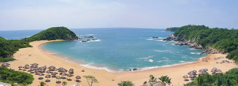 Bahía de aguas claras rodeada de vegetación tropical en Huatulco, costa de Oaxaca.