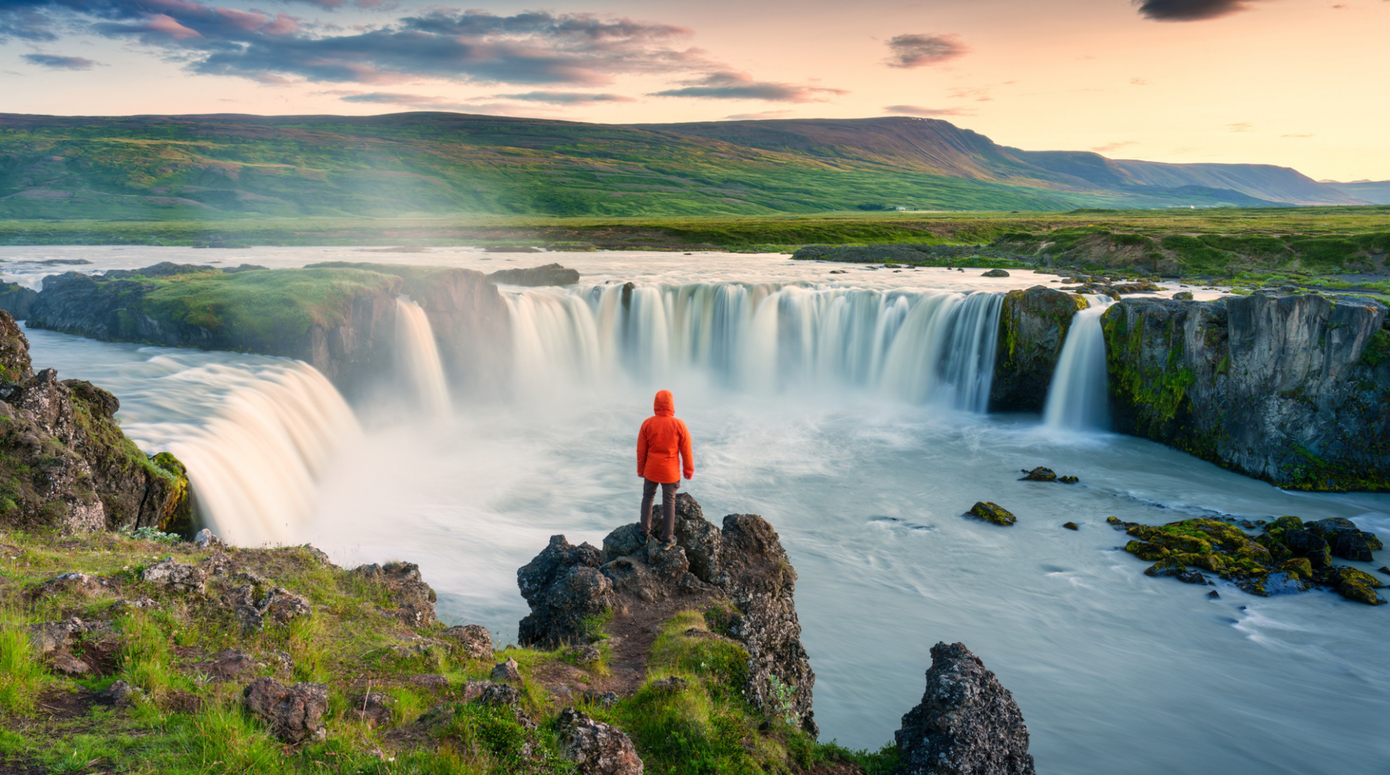 Turista davanti alla cascata Godafoss in Islanda al tramonto